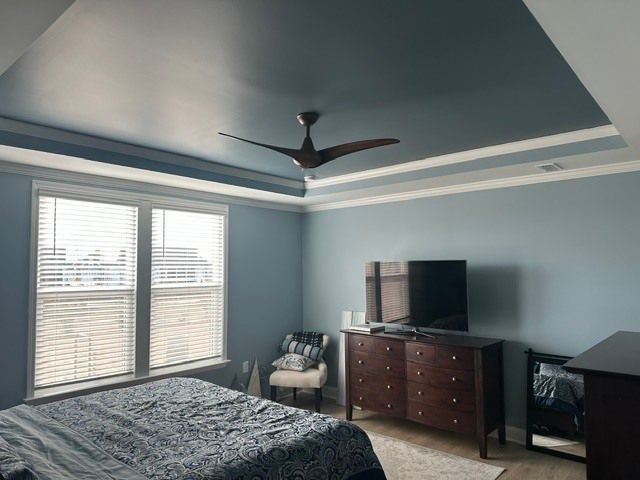Blue bedroom with a bed, dresser, TV, window blinds, and ceiling fan