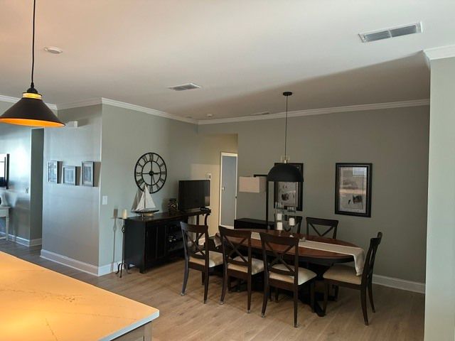 Open dining area with dark wood table, chairs, pendant lights, and gray walls in a modern home.