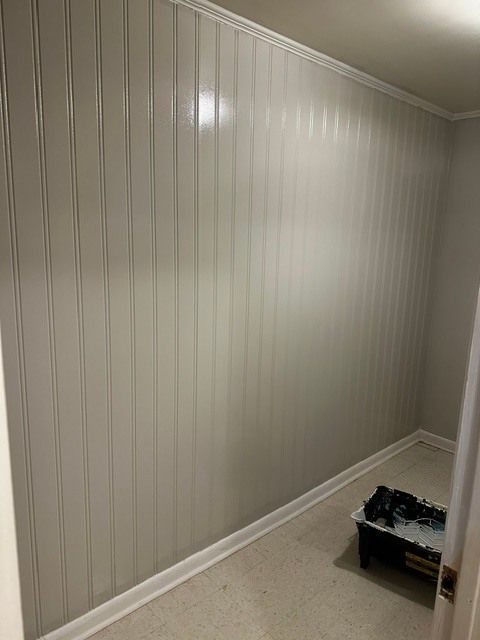 Empty beige paneled room with white trim and a small toolbox on the floor.