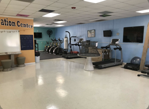 Small gym room with treadmills, exercise bikes, and a wall-mounted TV