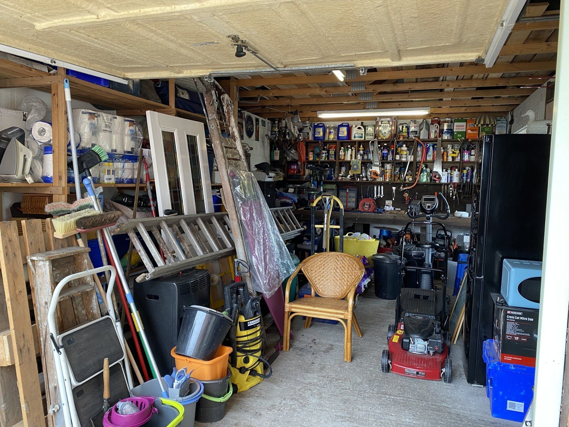 A messy and cluttered garage used as storage for junk that has been collected over the years;