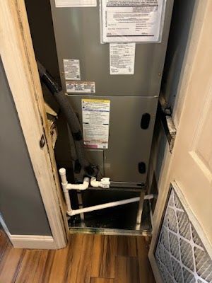 An air conditioner is sitting in a closet next to a door.