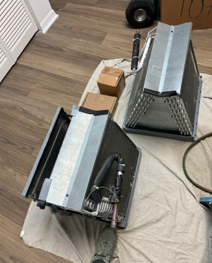 Two air conditioners are sitting on a white towel on the floor.