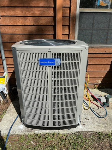 A large air conditioner is sitting on the side of a house.