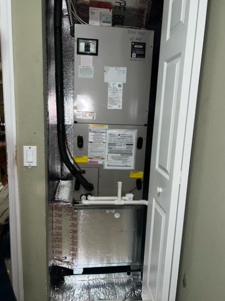 An air conditioner is sitting in a closet next to a door.