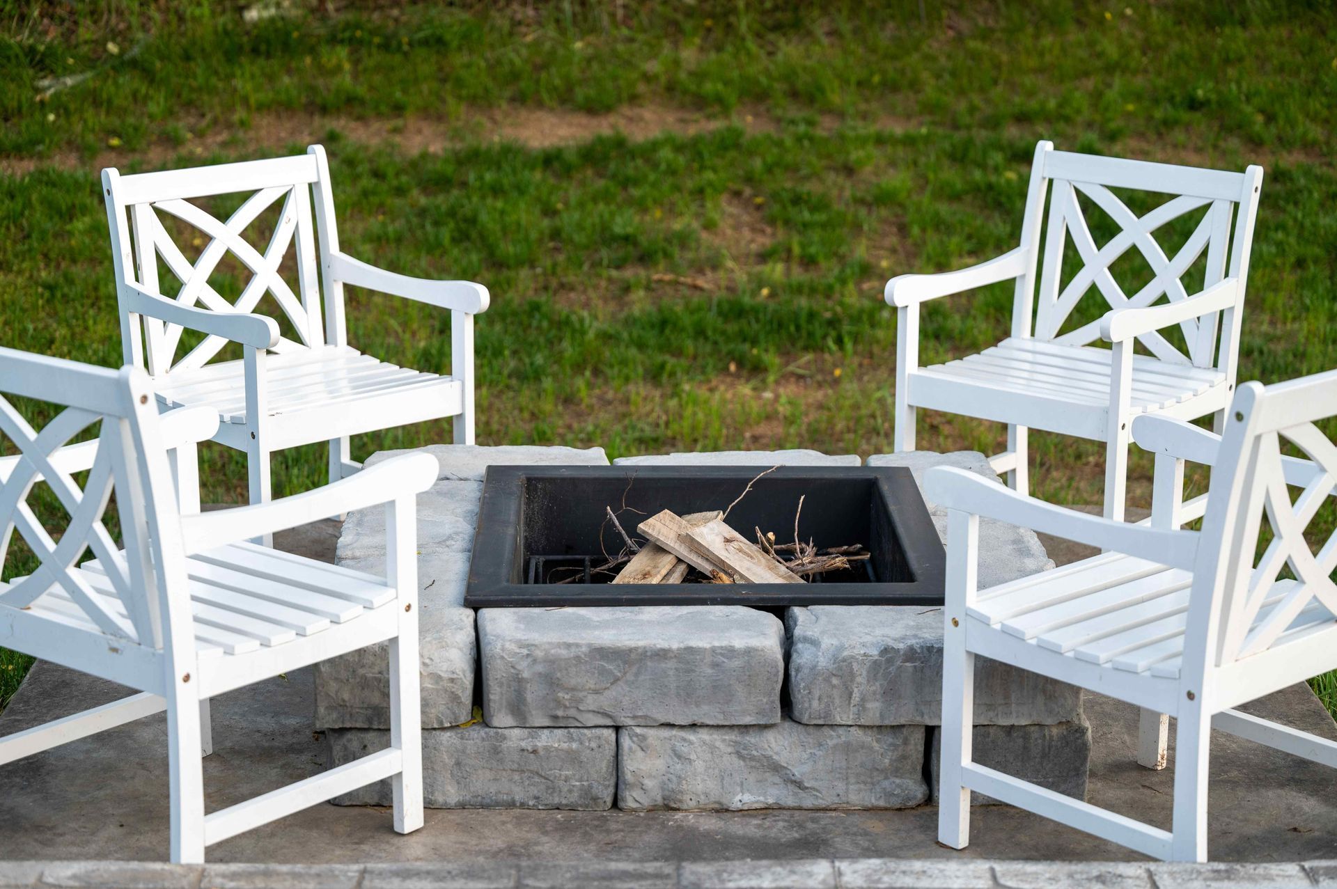 Backyard fire pit with four chairs surrounded by grass