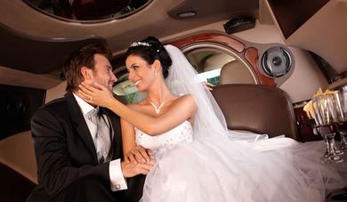 Los novios se abrazan en una limusina de lujo, sonriendo bajo una tenue iluminación interior.