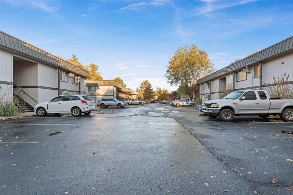 Apartment buildings with parked cars in a parking lot on a cloudy day.