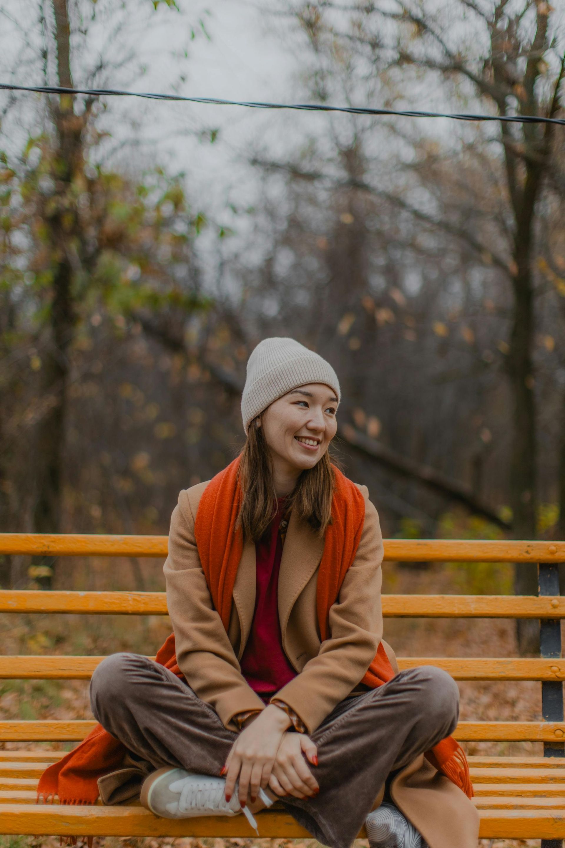 A woman is sitting on a park bench with her legs crossed.