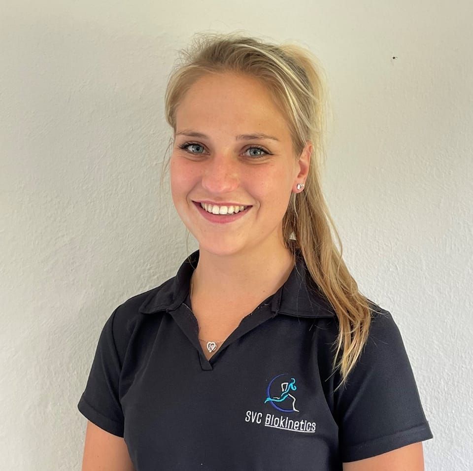Woman with blonde hair smiles at the camera, wearing a black polo shirt with a logo.