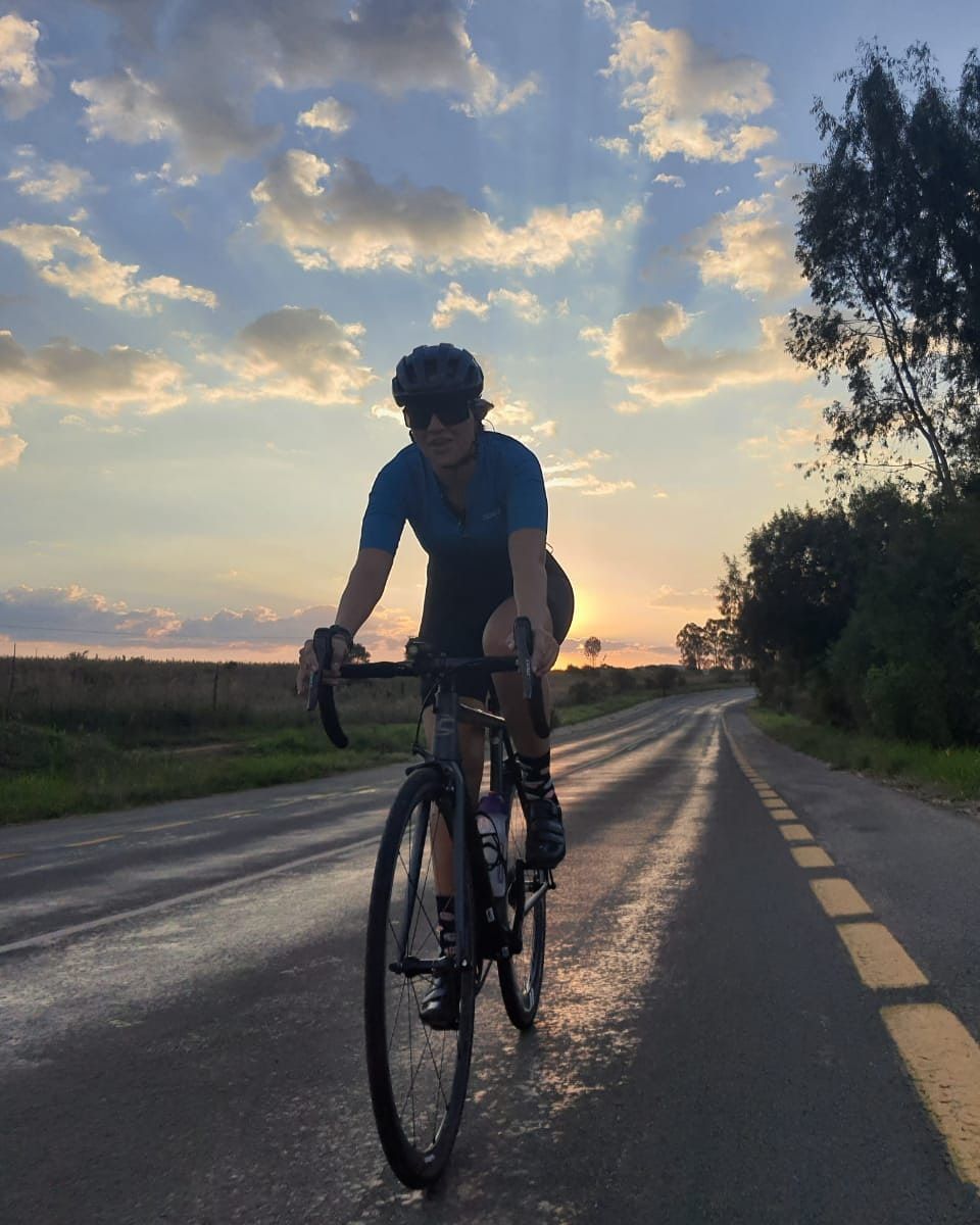 Cyclist riding on a road with a sunset background.