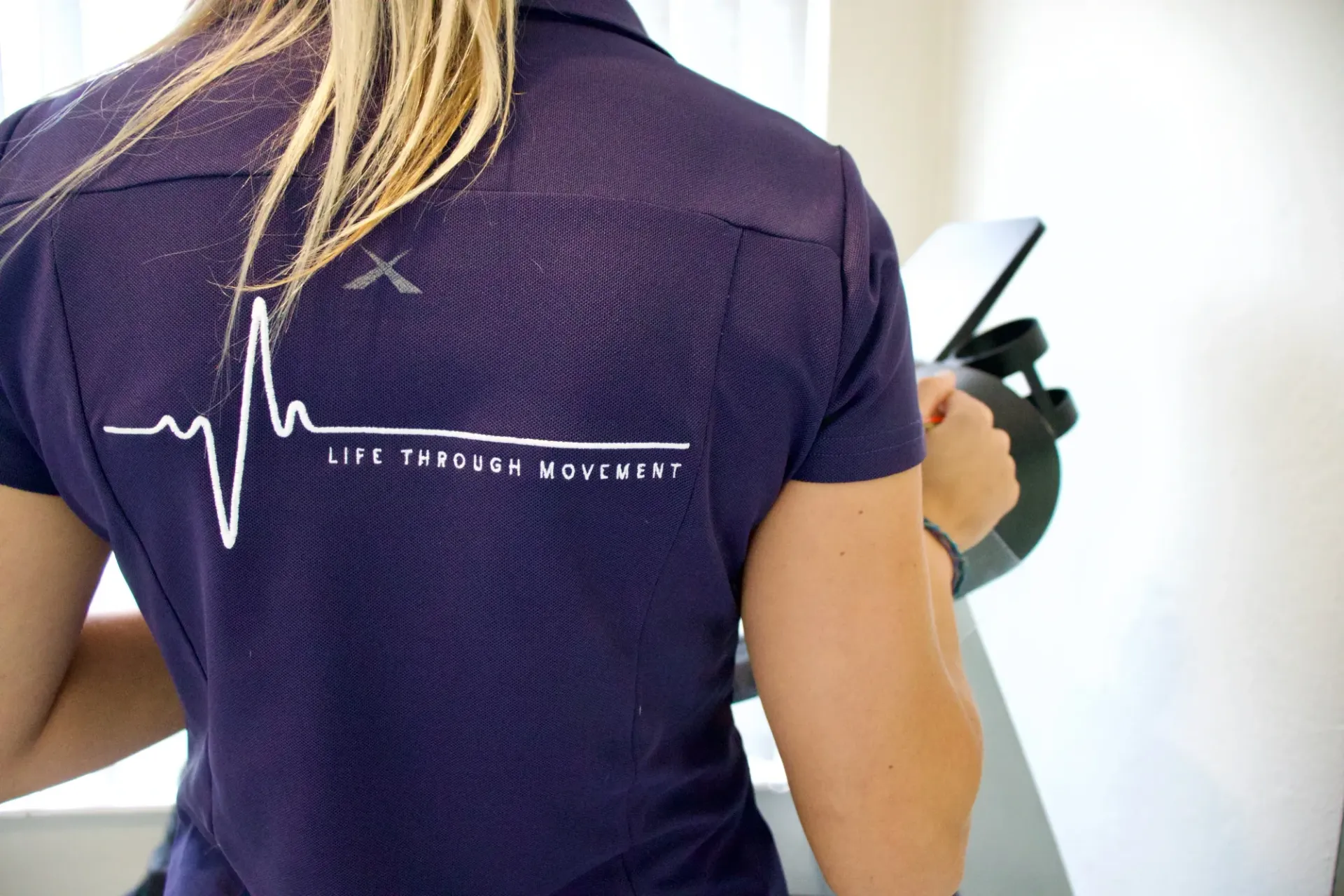 Person in purple shirt with logo: Heartbeat line and 