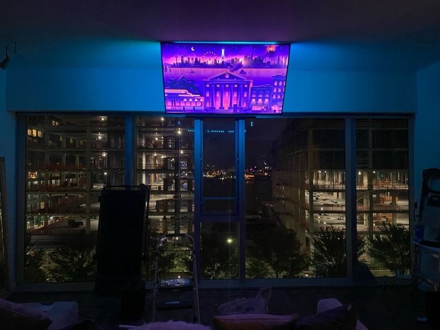 A living room with a flat screen tv hanging from the ceiling