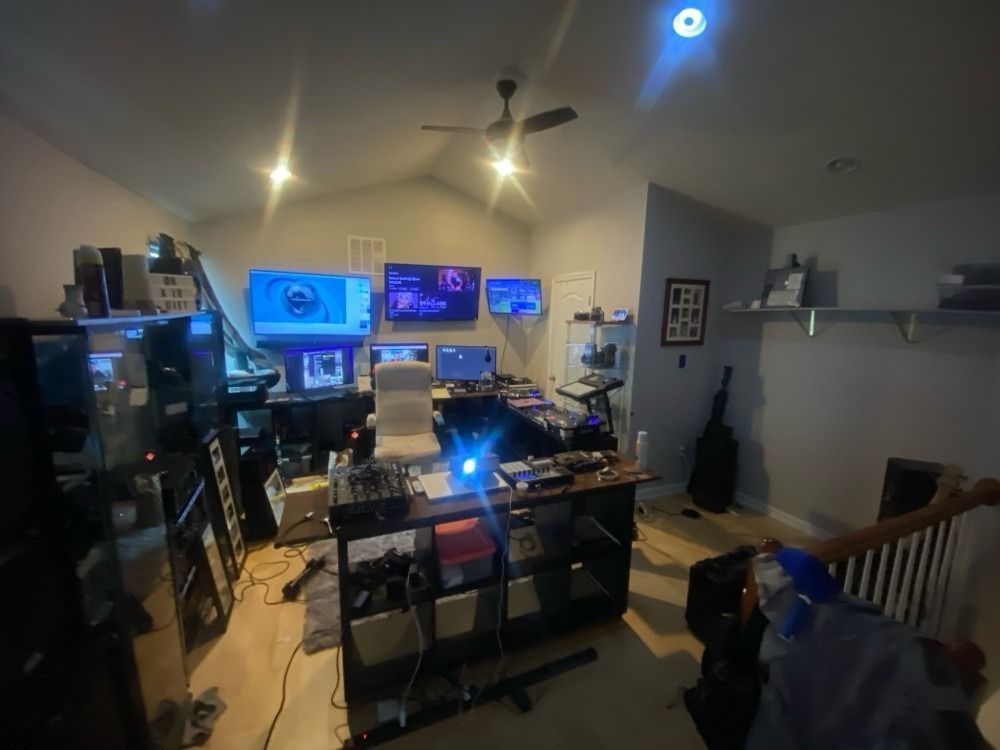 A room with a lot of computers and a ceiling fan