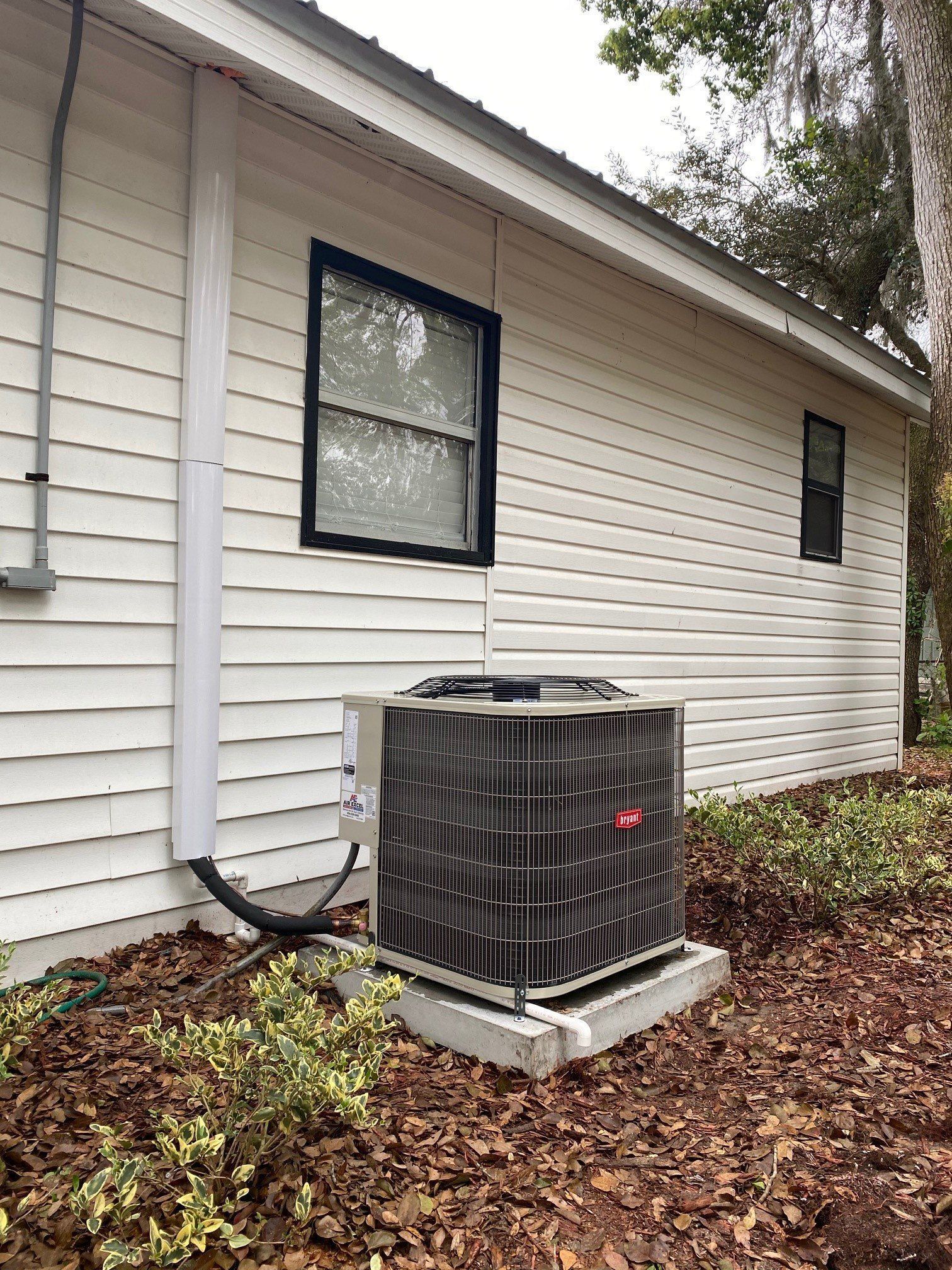 An air conditioner is sitting on the side of a house next to a window.