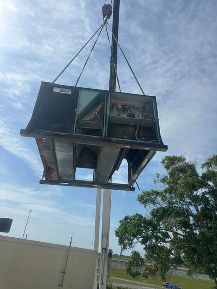 A large piece of equipment is being lifted by a crane.