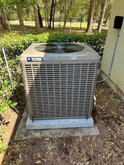 A york air conditioner is sitting outside of a house.