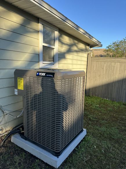 A large air conditioner is sitting on the side of a house.