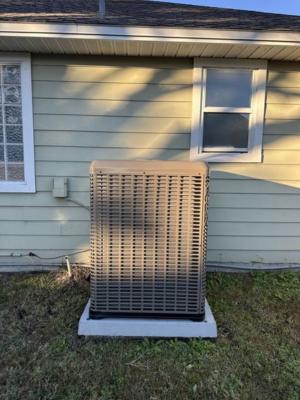 An air conditioner is sitting on the side of a house.