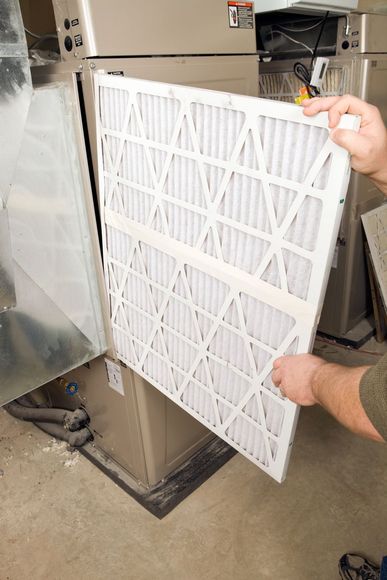 A person is holding a filter in front of an air conditioner.