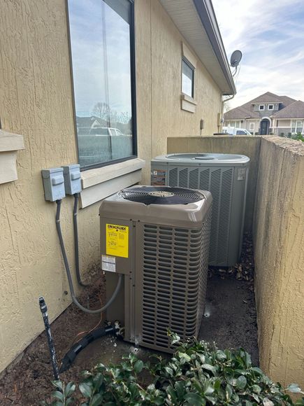 An air conditioner is sitting outside of a house next to a window.