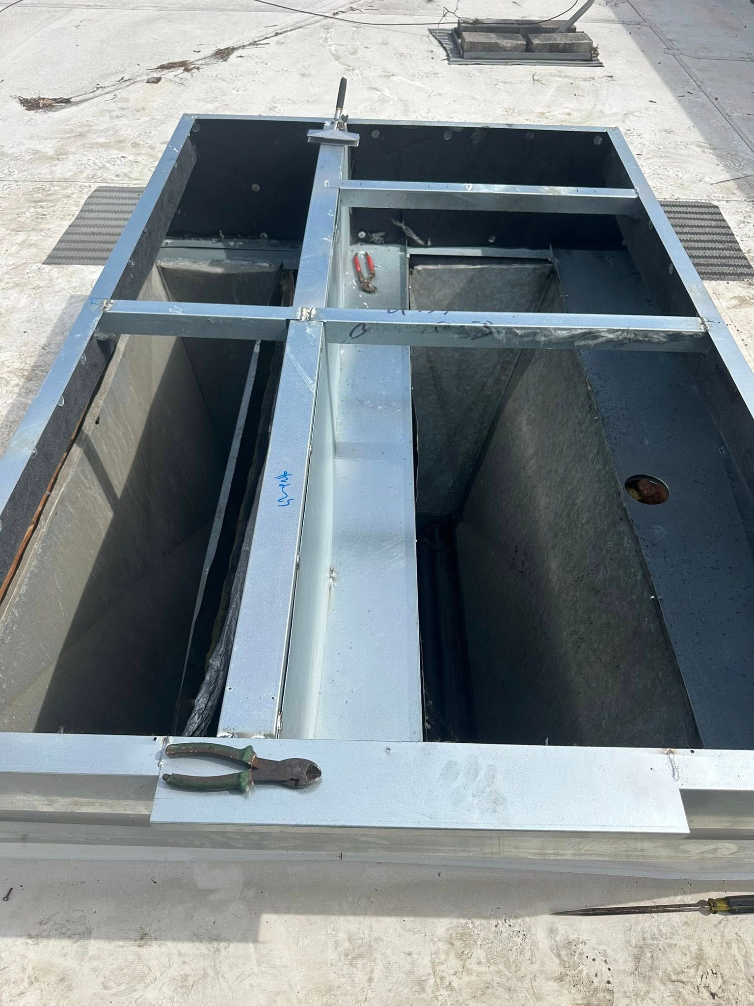 A large metal box with a metal frame is sitting on the ground.