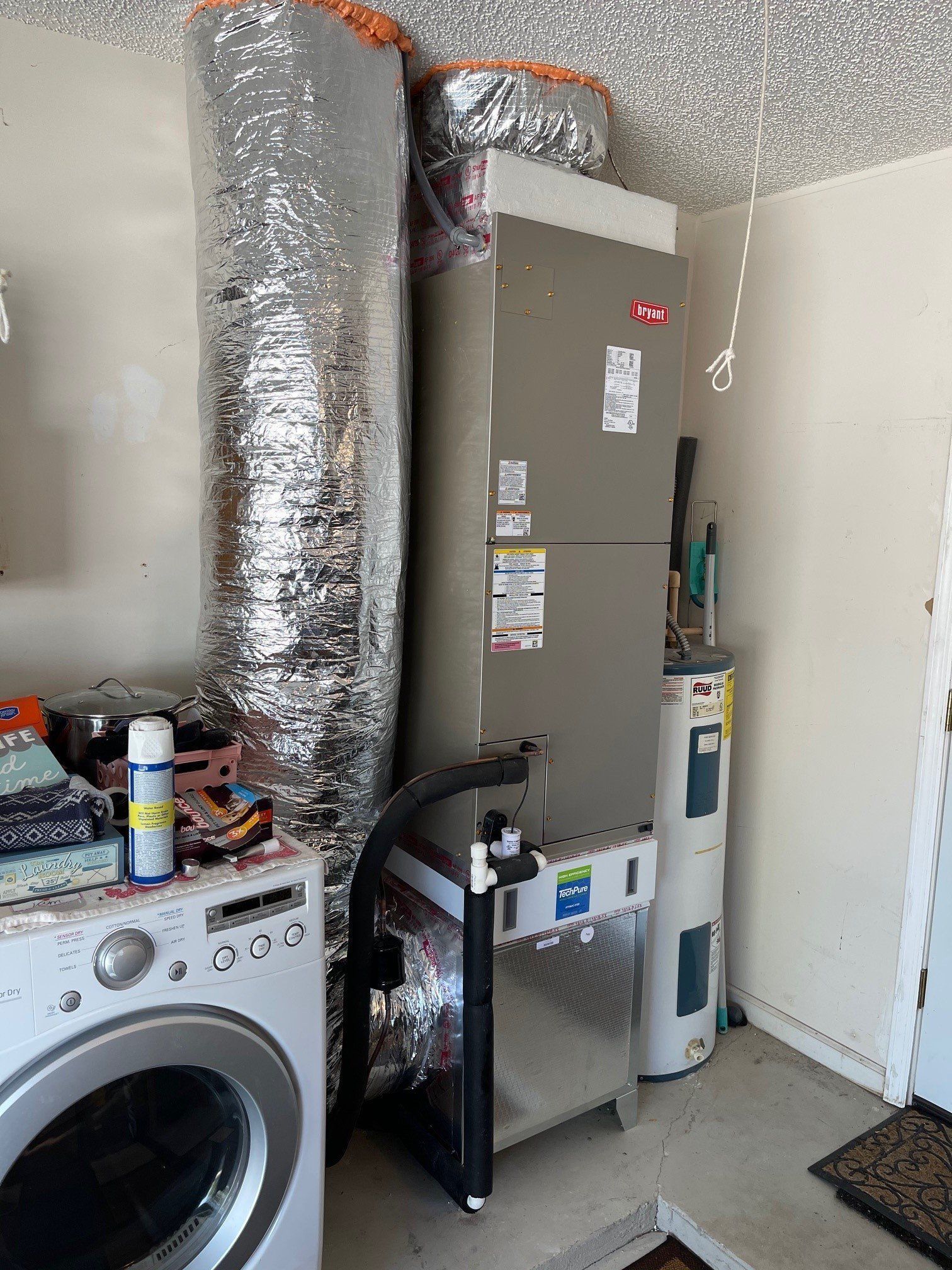 A washer and dryer are sitting next to a refrigerator in a laundry room.