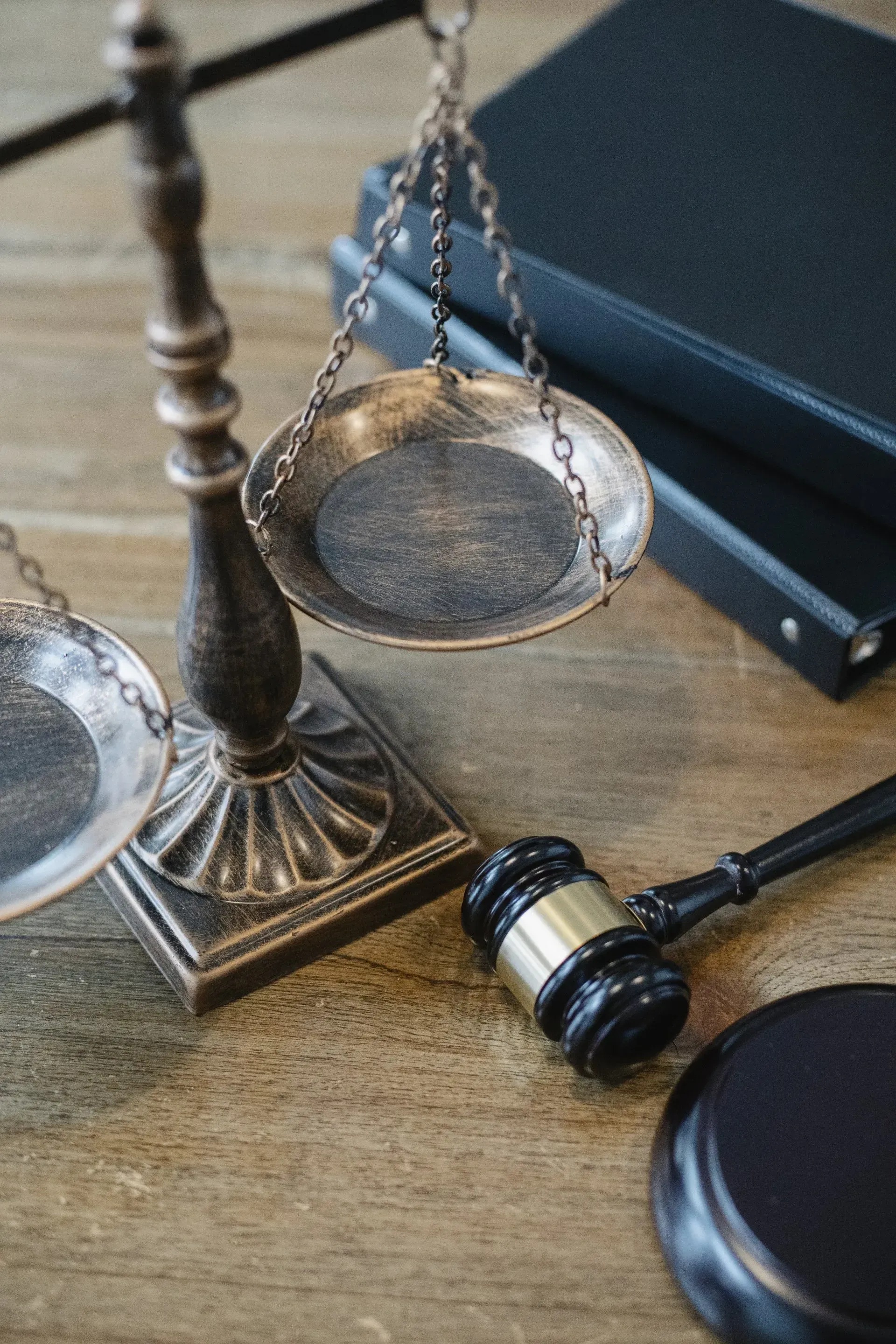 Scales of justice, gavel, and books on a wooden surface, symbolizing law and legal proceedings.