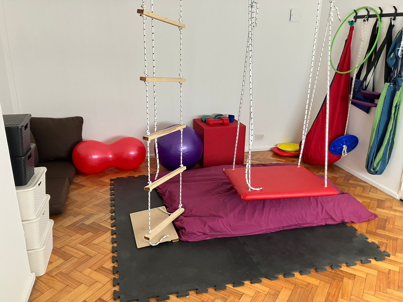 Una sala de terapia de integración sensorial con un columpio de plataforma.