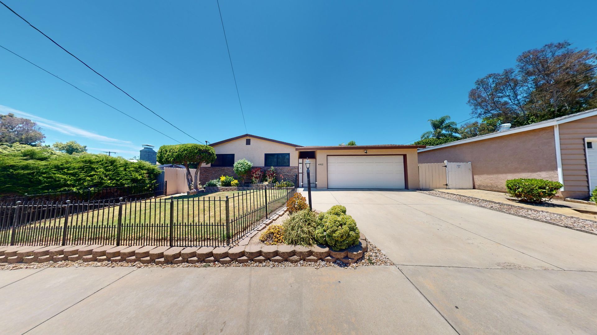 House exterior with driveway, garage, and front yard landscaping on a sunny day.