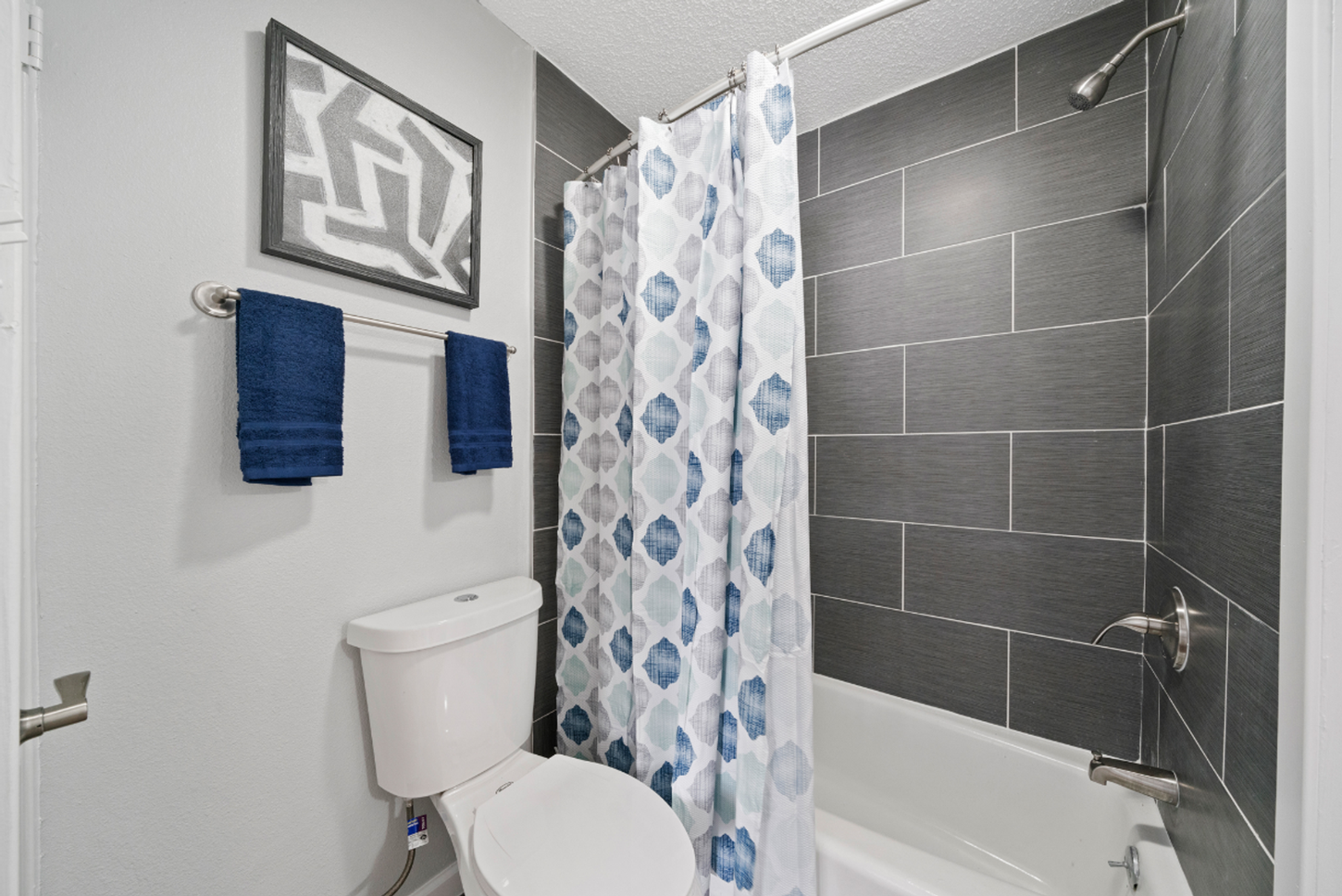 A bathroom with a toilet , bathtub and shower curtain.