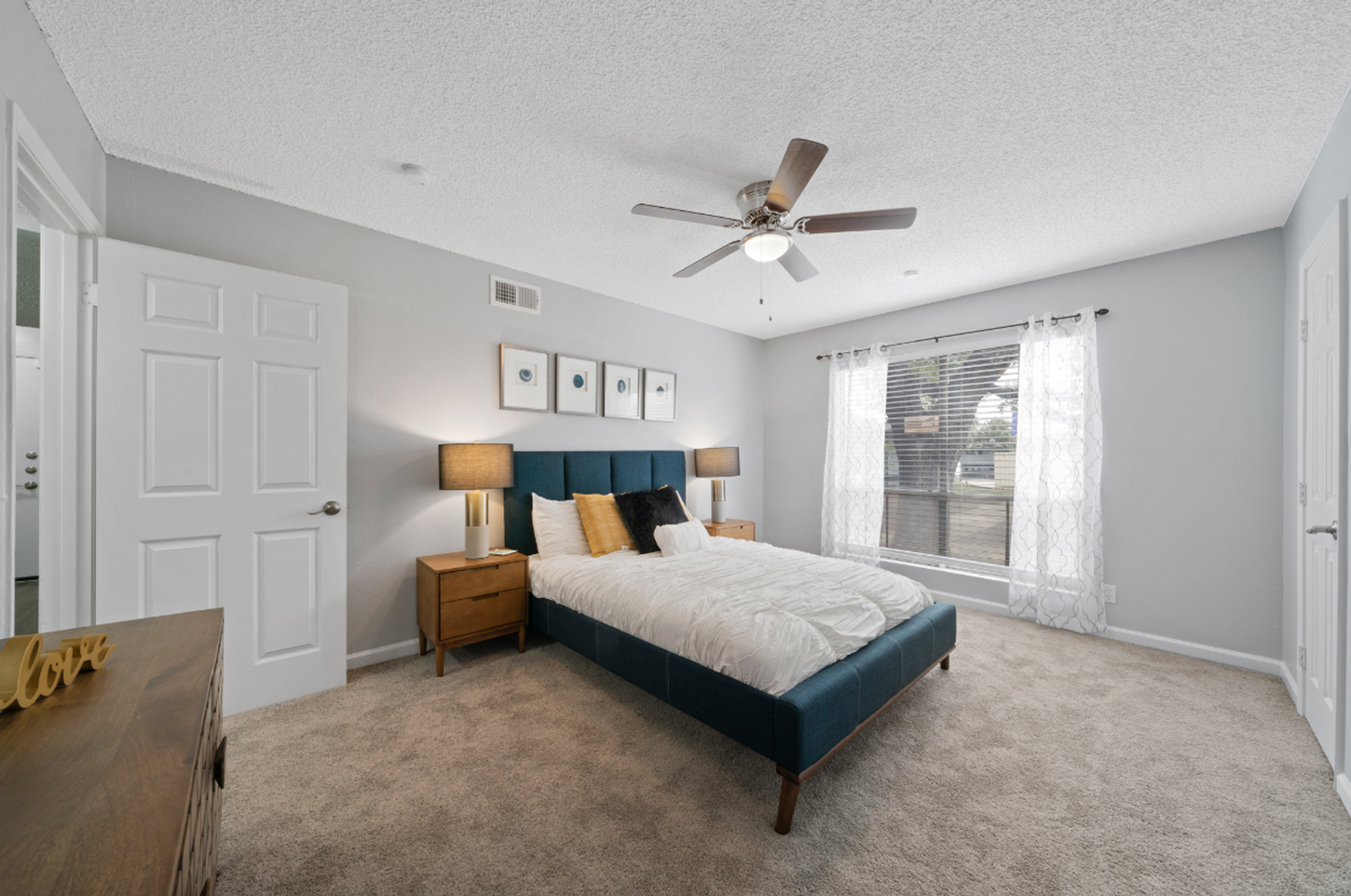 A bedroom with a large bed and a ceiling fan.