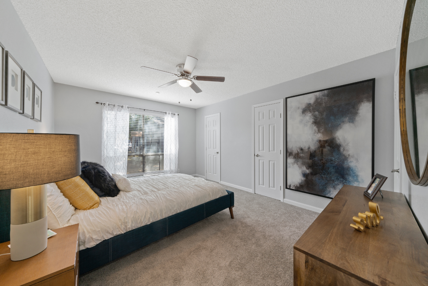 A bedroom with a large bed , nightstand , mirror and ceiling fan.