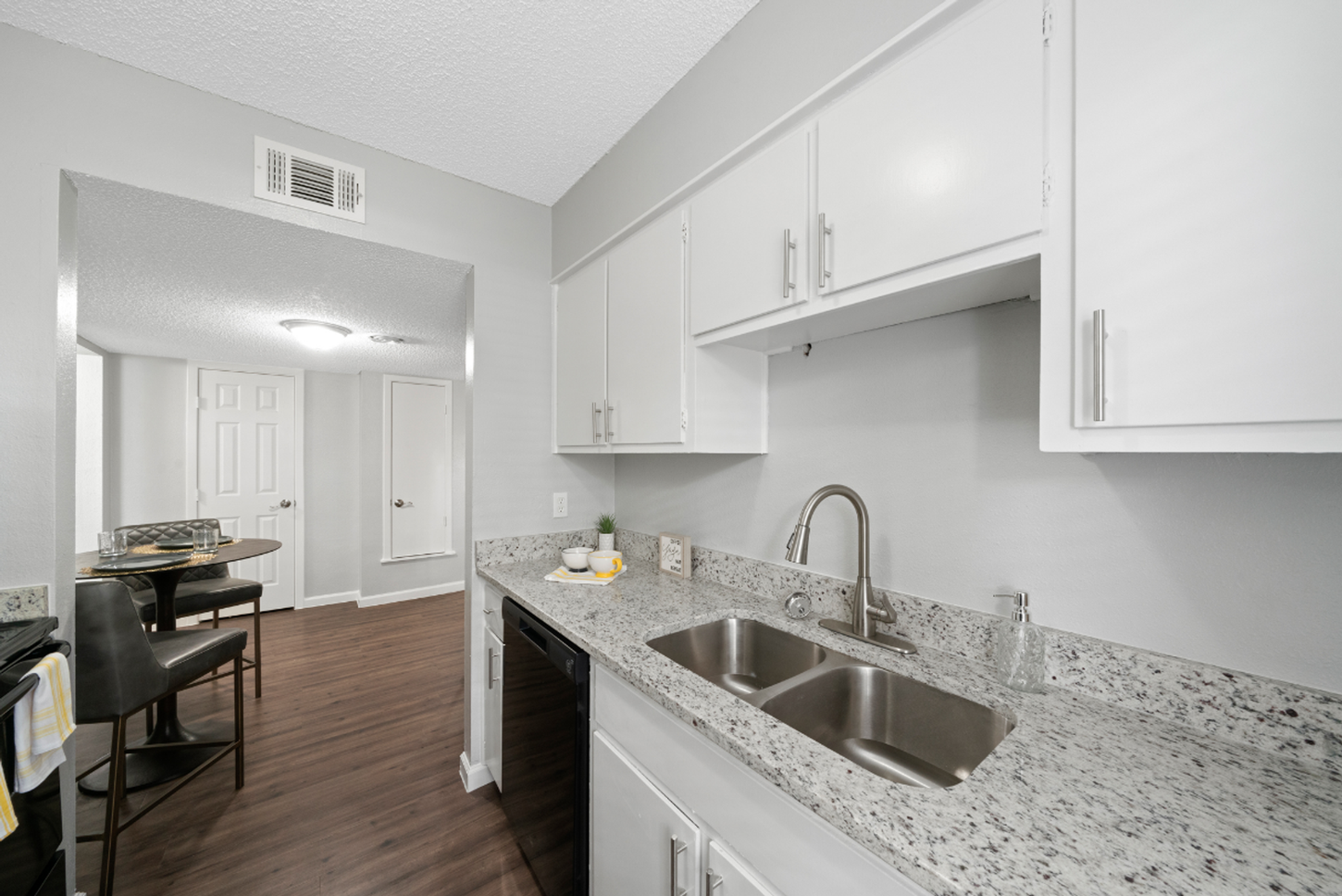 A kitchen with white cabinets , granite counter tops , a sink and a dishwasher.