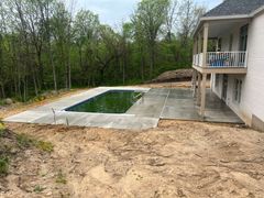 There is a large swimming pool in the backyard of a house.