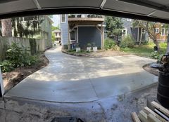 A concrete driveway is being built in front of a house.