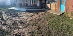 A muddy yard in front of a house with a blue door.