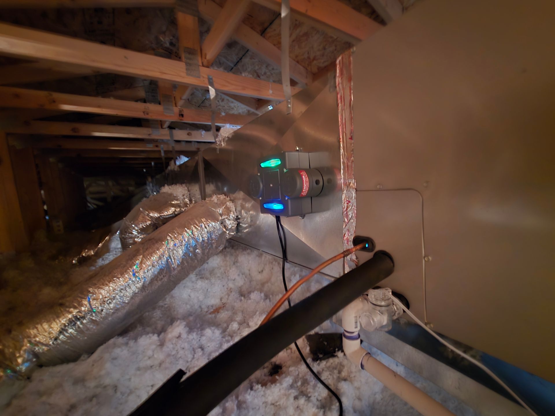 Attic with HVAC unit; green and red lights on unit, insulation and ductwork visible.