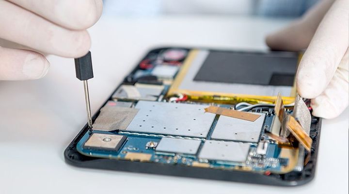 Hands repairing a smartphone with a precision tool, exposed internal components visible.