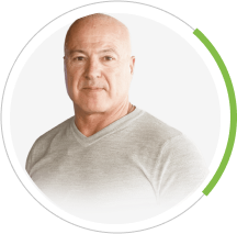 A bald man wearing a grey sweater is in a circle with a green line.