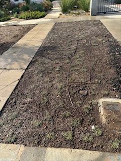A large pile of dirt is sitting next to a sidewalk.