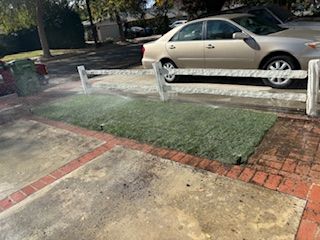 A car is parked in a driveway next to a fence.