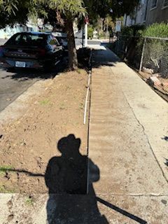 A shadow of a man in a cowboy hat is cast on a sidewalk.