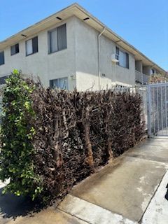 A building with a fence and a hedge in front of it.