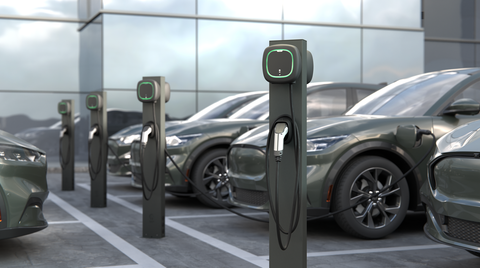 A row of electric cars are being charged at a charging station.