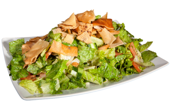 A salad with lettuce tomatoes and pita chips on a white plate