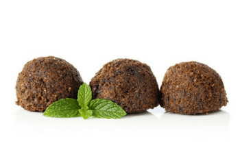 Three falafel balls with mint leaves on a white background