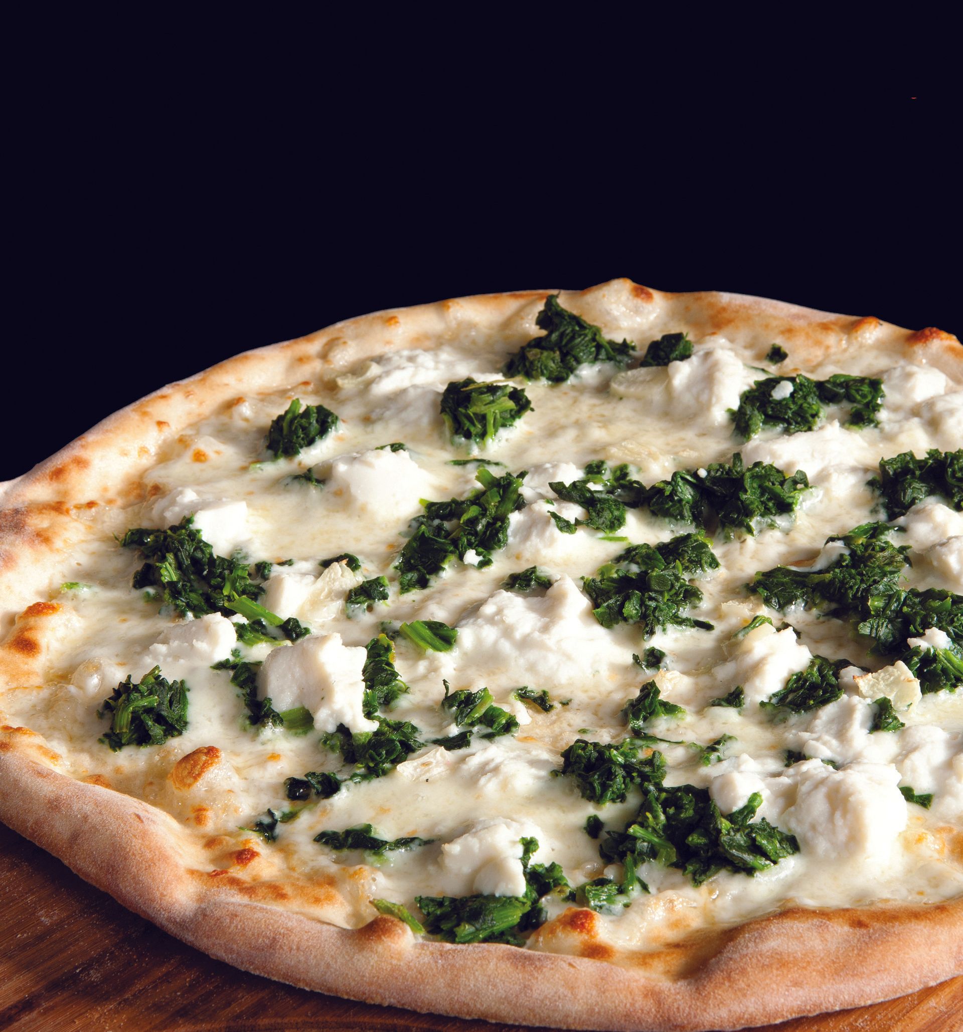 A pizza with a lot of cheese and greens on it