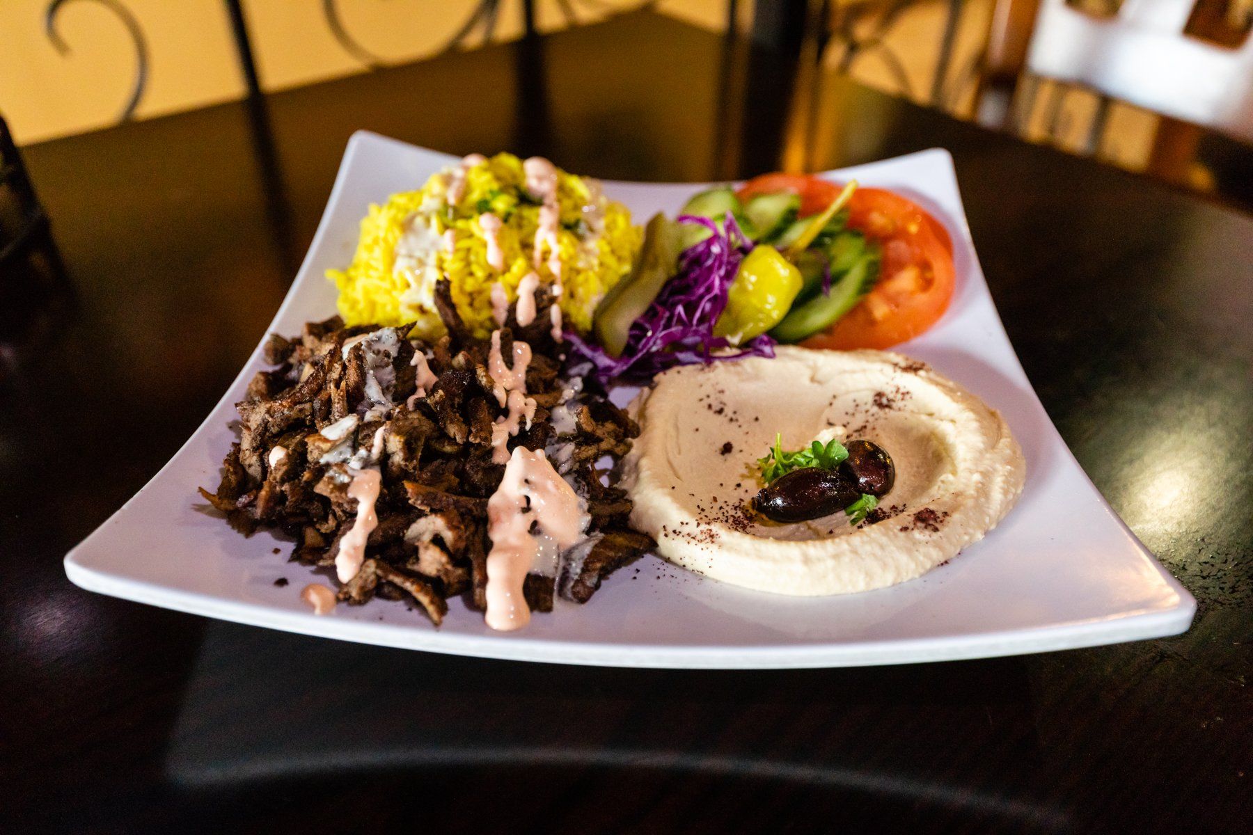 A plate of food with hummus rice and vegetables on a table