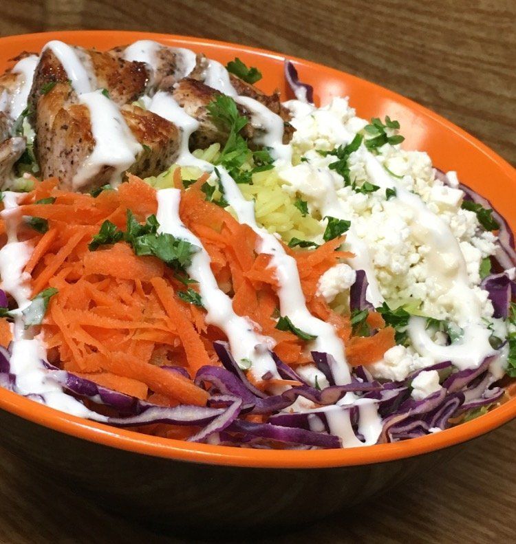 A close up of a bowl of food with carrots and cabbage